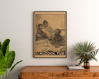 Póster histórico – L’Alcool tue – Eugène Burnand, enmarcado sobre una cómoda de madera, entre plantas.