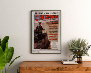 Póster Normandía vintage – Cherbourg, chemins de fer de l’Ouest, enmarcado sobre una cómoda de madera, entre plantas.