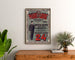 Vintage advertisement Au Phare de la Loire, clothing, poster framed above a wooden dresser between plants.