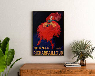 Cartel publicitario vintage Cognac Richarpailloud, enmarcado sobre una cómoda de madera, entre plantas.