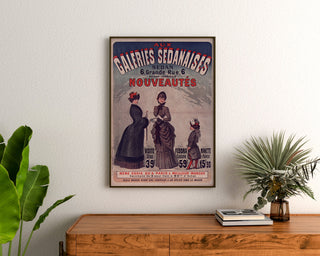 Vintage advertisement Galeries sedanaises, Nouveautés, framed above a wooden dresser between plants.