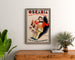 Póster publicitario vintage Oscaria, calzado, enmarcado sobre una cómoda de madera, entre plantas.