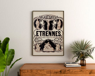 Vintage advertising poster Verdun, statuettes and gifts, framed above a wooden dresser, between plants.