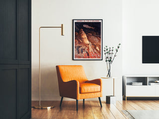 Vintage tourist poster – Grottes de Lacave, Rocamadour framed in a living room with an orange armchair and a floor lamp.