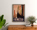 Vintage travel poster – Venezia, gondola prows, framed above a wooden dresser between plants.
