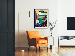 Póster turístico vintage – Vichy, manantiales y turismo, enmarcado en un salón con un sillón naranja y una lámpara de pie.