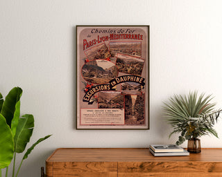 Póster vintage Dauphiné, excursiones PLM, enmarcado sobre una cómoda de madera, entre plantas.