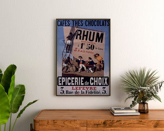 Póster vintage Épicerie Lefèvre, cafés y chocolates, enmarcado sobre una cómoda de madera, entre plantas.