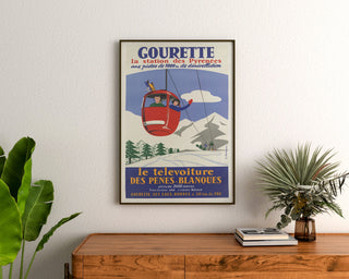Vintage Gourette Télévoiture poster, framed above a wooden dresser between plants.