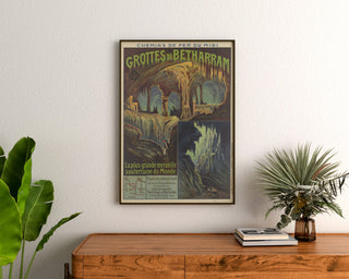 Póster vintage Grutas de Bétharram, enmarcado sobre una cómoda de madera, entre plantas.