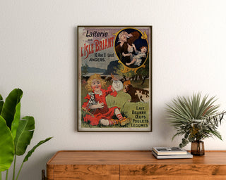 Póster vintage Laiterie de l’Isle Briant, Angers, enmarcado sobre una cómoda de madera, entre plantas.