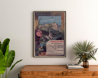 Póster vintage de Lourdes, estaciones balnearias, enmarcado sobre una cómoda de madera, entre plantas.