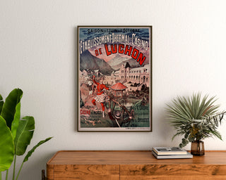 Vintage Luchon poster, casino and spa, framed above a wooden chest, between plants.