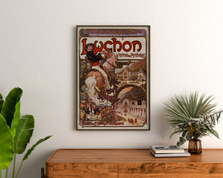 Vintage Luchon poster, the queen of the Pyrenees, framed above a wooden chest, between plants.