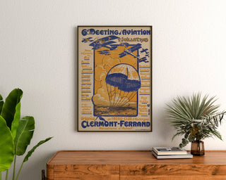 Vintage aviation meeting poster, Clermont-Ferrand, framed above a wooden dresser, between plants.
