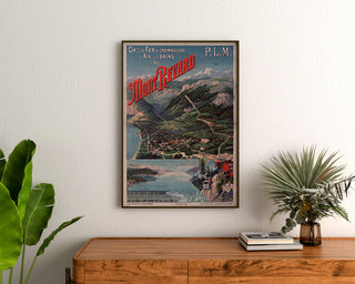 Vintage Mont-Revard poster, rack railway, framed above a wooden dresser, between plants.