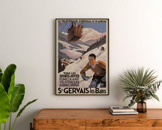 Cartel vintage Saint-Gervais, Mont-d’Arbois, enmarcado sobre una cómoda de madera, entre plantas.