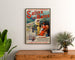 Póster vintage Salins-les-Bains (Jura), enmarcado sobre una cómoda de madera, entre plantas.