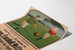 Póster vintage Sarreguemines, partido de fútbol, presentado sobre una hoja curvada, visto en perspectiva.