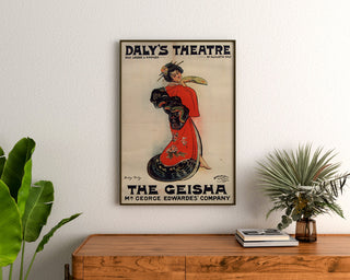 Cartel vintage The Geisha, Daly’s Theatre, enmarcado sobre una cómoda de madera, entre plantas.