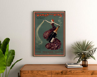 Cartel vintage Woman and Wine, Princess’s Theatre, enmarcado sobre una cómoda de madera, entre plantas.